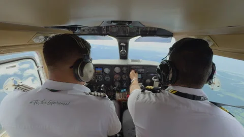 Two Pilots Operating Small Aircraft Cockpit During Flight Over Green Landscape. Stock Footage 338361282