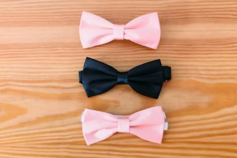 Two pink bow-ties and one black lying on the floor. Stock Photos