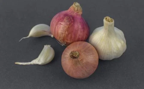 Two pink colored medium size onion and a white garlic beside some garlic seed Stock Photos