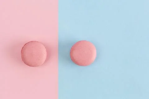 Two pink macarons on divided pink-blue background. Top view with copy space Stock Photos
