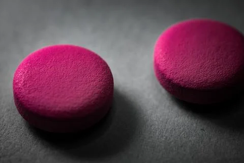 Two pink pills on a gray surface. Stock Photos