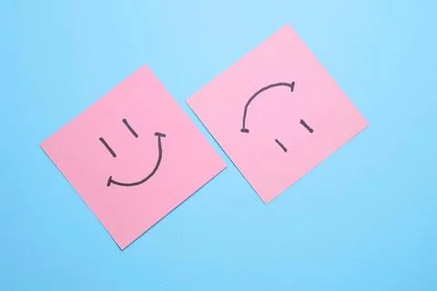 Two pink sticky notes with smiley faces on blue background Stock Photos