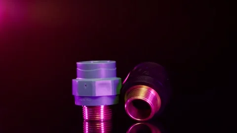 Two pipe couplings sit close together under purple light, Studio Product Shot Stock Footage 342319192
