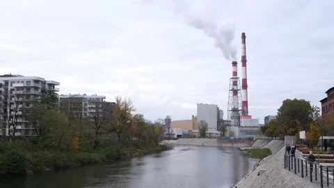 Two pipes of the heating station release white steam among modern city buildings Stock Footage 124356018