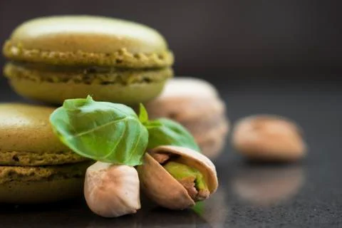 Two pistachio macarons with nuts on dark background Stock Photos