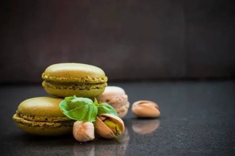 Two pistachio macarons with nuts on dark background Stock Photos