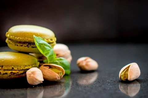 Two pistachio macarons with nuts on dark background Foto stock