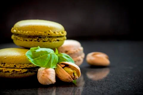 Two pistachio macarons with nuts on dark background Foto stock