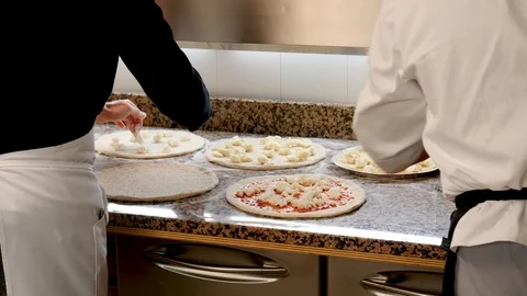 Two pizza chefs topping multiple pizzas  Stock Footage 86897823