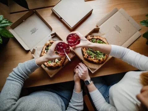 Two pizzas in boxes on a table, lemonade in hands, clink glasses Stock Photos
