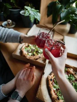 Two pizzas in boxes on a table with lemonade in hands, clink glasses, pov Stock Photos