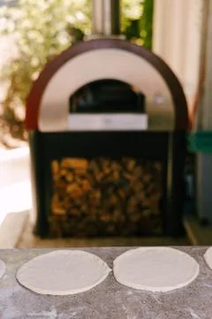 Two pizzas from raw dough on the background of the pizza oven. Stock Photos