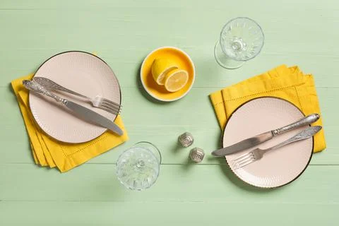 Two place settings with pink plates, yellow napkins, and vintage silverware o Stock Photos