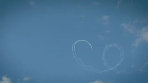 Two planes completing a loop maneuver with smoke trails in a cloudy blue sky. Stock Footage 340164598