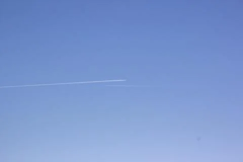 Two planes fly towards each other. Inversion trail of clouds from the plane Stock Photos