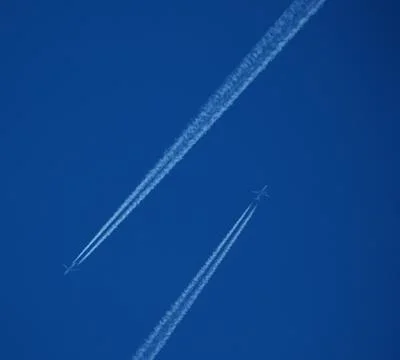 Two planes in the sky, two airplane tracks in the blue sky, contrails Stock Photos