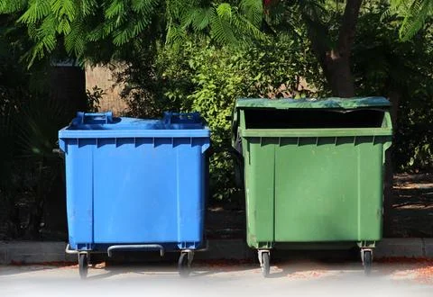 Two plastic bins, garbage containers in the middle of the street. Blue, green Stock Photos