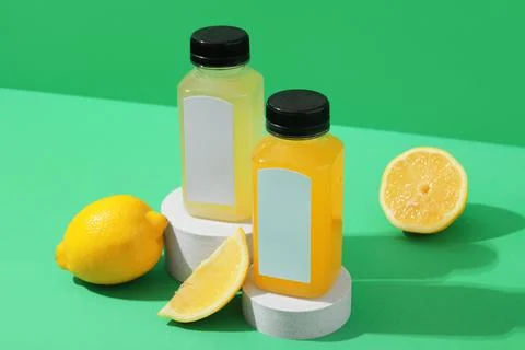 Two plastic bottles of fresh lemon and orange juice with blank labels on whit Stock Photos