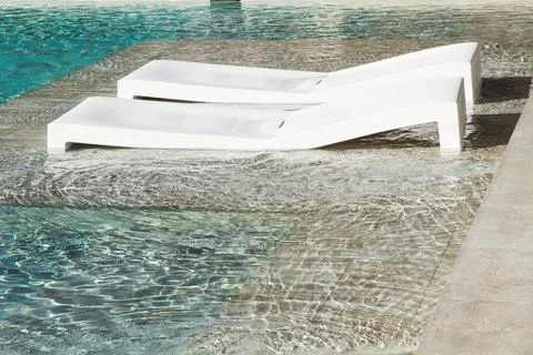 Two plastic deck chairs in a swimming pool Foto stock