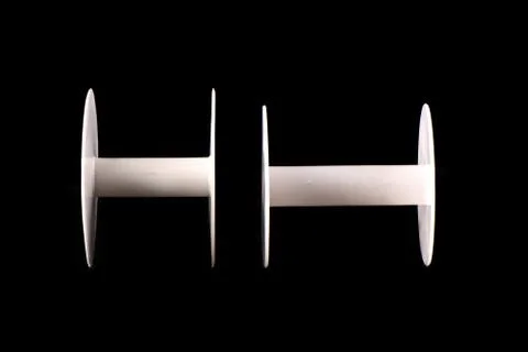 Two plastic empty spools of tape or strips of cloth on a black b Stock Photos