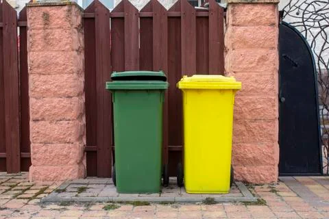 Two plastic garbage containers are in the yard near the fence, garbage collec Foto stock