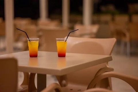Two Plastic Glasses With Cold Cocktail Sunrise With Black Cocktail Straw on Stock Photos