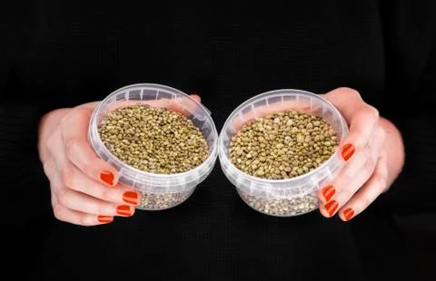 Two plastic jars with hemps in woman's hands Stock Photos