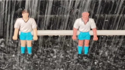Two plastic soccer figurines in white shirts and blue shorts stand on a field Stock Footage 338172549