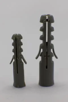 Two plastic wall plugs, one larger than the other, are shown against a white  Foto stock