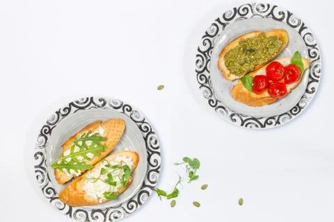 Two plates with different types of bruschetta on a white background. Overhead Stock Photos