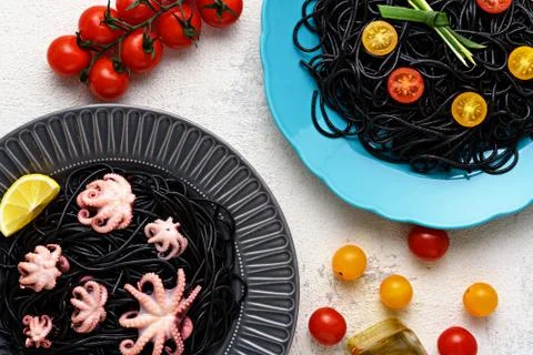 Two plates of spaghetti with cuttlefish ink with octopuses and yellow, red ch Stock Photos