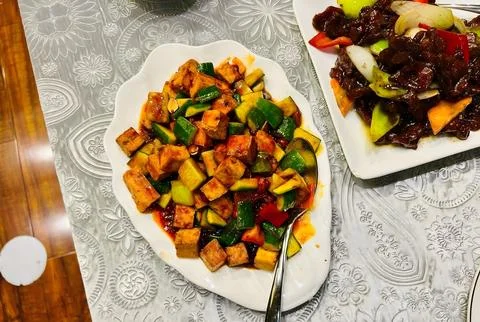 Two Plates of Stir-Fried Vegetables and Tofu on a Patterned Tablecloth Stock Photos