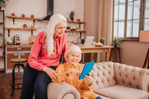 Two pleasant-looking elderly grey-haired women having a video chat Stock Photos