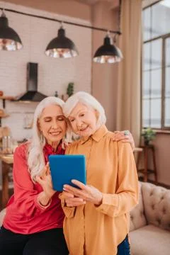 Two pleasant-looking elderly grey-haired women standing in the room Stock-Fotos