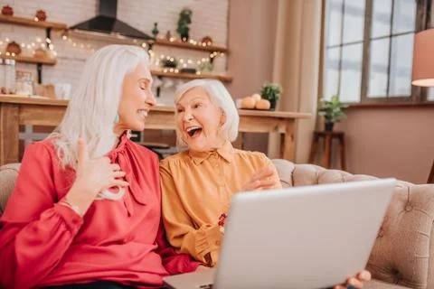 Two pleasant-looking elderly grey-haired women laughing loudly Stock Photos