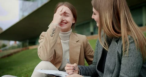 Two pleasure mixed race students female doing homework exercise outside campus Stock Footage 120745739