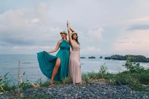 Two plus size models in long dresses with wreaths of flowers on their heads pose Stock Photos