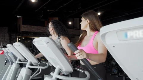 Two plus size women talking while working out at the gym on elliptical trainer Video stock 115078465