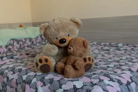 Two Plush Teddy Bears Cuddling on a Bed With a Colorful Knitted Blanket Stock Photos