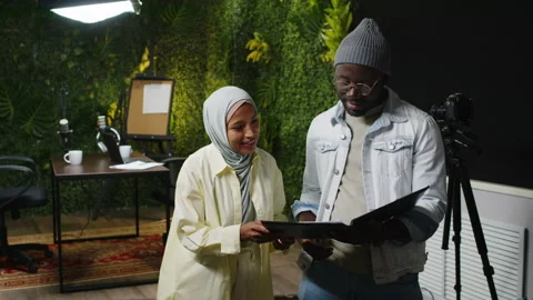 Two Podcast Cohosts Discussing Script in Recording Studio Video stock 270280699