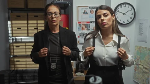 Two policewomen in office with badges, clock, map, and missing posters indi.. Stock Footage 276545683