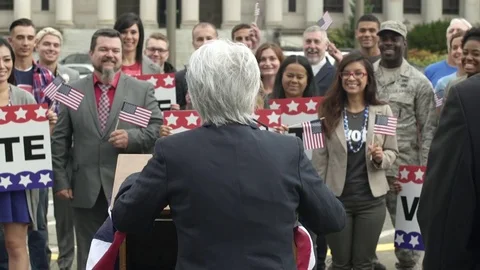 Two politicians giving a speech in front of an applauding crowd 動画素材 76235631