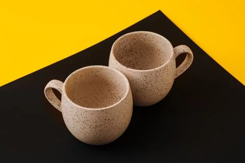 Two porcelain empty cups on a black and yellow background, copy space Foto stock
