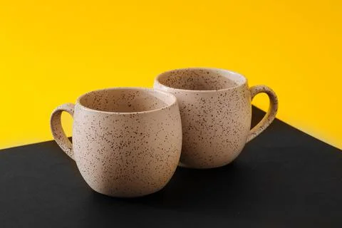 Two porcelain empty cups on a black and yellow background, copy space Stock Photos