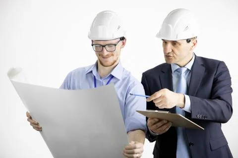 Two positive construction engineers look at drawing, making notes on clipboard Stock Photos