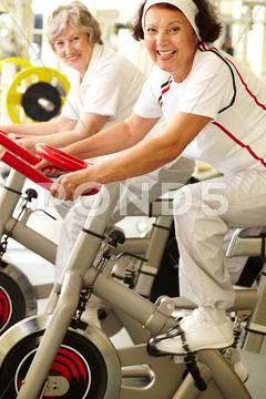 Two positive senior women exercising in gym Stock Photos