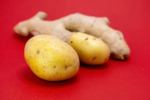Two potatoes and a piece of ginger on a red background. Stock-Fotos