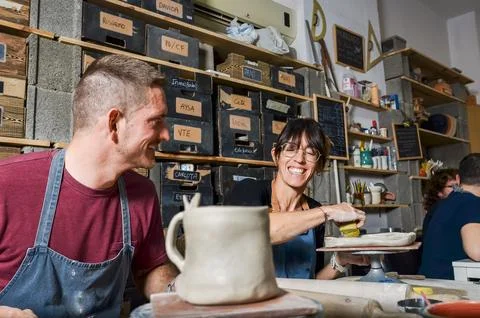 Two potters creating ceramics in workshop smiling and having fun Stock Photos