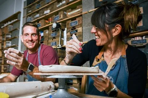 Two potters smiling and working clay in their workshop Stock Photos