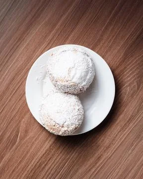 Two powdered pastries rest on a simple white plate Фото